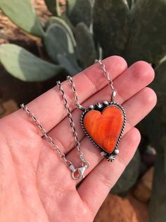 Sterling silver and orange spiny. Rope trim and sterling drop accents. The heart measures 1 1/8" wide. Adjustable link chain. 19" total length. Stamped sterling and signed by artist. Artisan Sterling Silver Heart Necklace, Artisan Heart-shaped Sterling Silver Necklace, Unique Orange Sterling Silver Necklace, Red Southwestern Sterling Silver Necklace, Southwestern Silver Heart-shaped Jewelry, Sterling Silver Pendant Necklace In Orange, Southwestern Silver Heart Jewelry, Southwestern Silver Heart Shaped Jewelry, Orange Heart Charm Jewelry