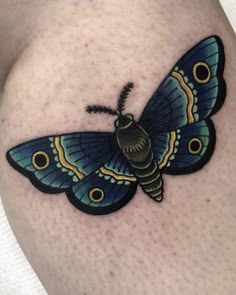 a small blue butterfly tattoo on the thigh