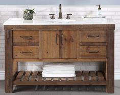 a bathroom vanity with two sinks and towels on the bottom shelf, against a white brick wall