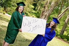 two women in graduation gowns holding a sign