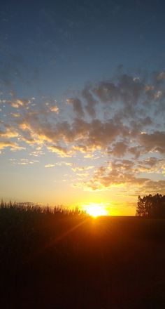 the sun is setting over an open field