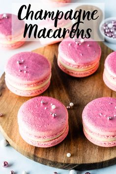 pink macaroons are on a wooden plate