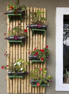 bamboo planters are arranged on the side of a wall with flowers growing in them