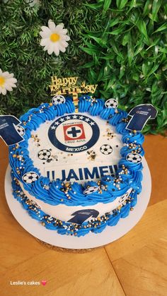 a birthday cake with blue frosting and soccer balls on it sitting on a table