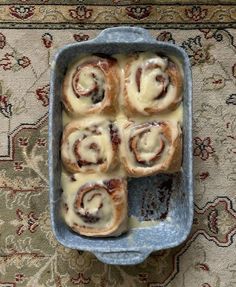 a pan filled with cinnamon rolls sitting on top of a rug