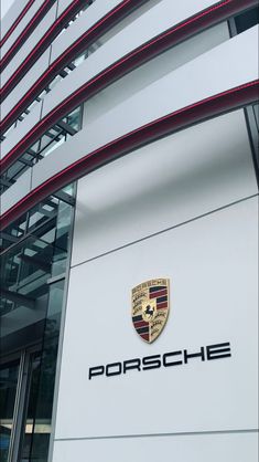 the porsche logo is on the side of a white building with red trimmings