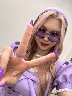 a woman in purple is making the v sign with her hand and wearing sunglasses on it