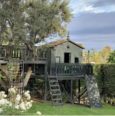 there is a tree house with a slide in the yard