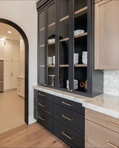 a kitchen with black cabinets and marble counter tops, along with an arched doorway leading to the dining room