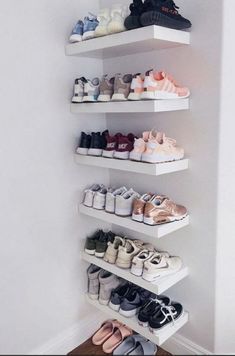 three white shelves filled with different types of shoes on top of each other in front of a wall