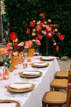 a table set with flowers and plates for an outdoor dinner or brunch party