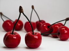 several red cherries with black stems on white surface