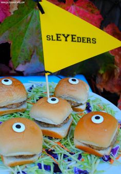 some hamburgers with eyes on them are sitting on a blue and white plate next to a yellow flag that says slyder's