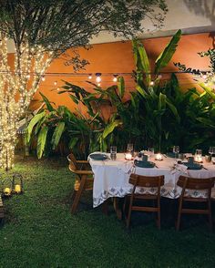 an outdoor dining area is lit up with fairy lights and greenery for a festive touch