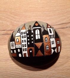 a painted rock sitting on top of a wooden table next to a wood floor with buildings