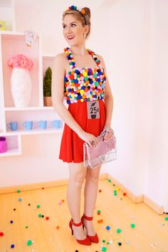 a woman in a red dress is holding a purse and posing for the camera with confetti all over her body