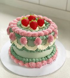 there is a three layer cake with strawberries on the top and green icing