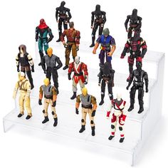 several toy action figures are displayed on a white stand with one figure in the middle