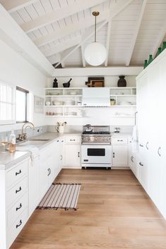 the kitchen is clean and ready for us to use it's white cabinets, wood flooring, and overhead lighting