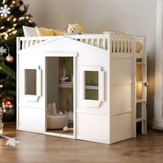 a white doll house next to a christmas tree