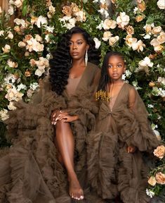 two women sitting next to each other in front of flowers