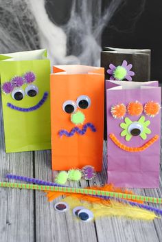 three halloween bags with googly eyes and flowers on them sitting next to a string