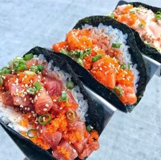 three sushi rolls with salmon, rice and green onions