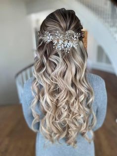 the back of a woman's head with wavy hair and flowers in her hair