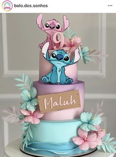 a three tiered cake decorated with pink and blue frosting, lillies and flowers