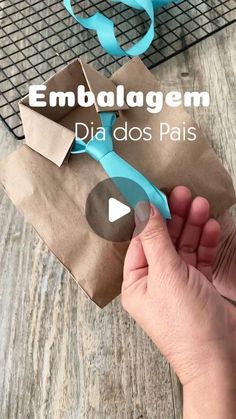 someone is holding a paper bag with scissors in it and the words embalgem dia dos pais