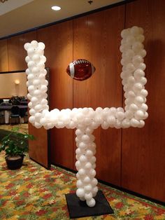 a football themed balloon sculpture in the shape of a letter h with a football on top