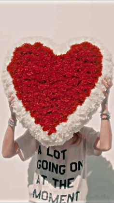 a woman holding up a heart shaped pillow with the words a lot going on at the moment