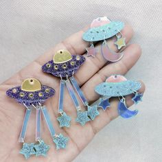 the hand is holding five different shaped brooches with stars and moon designs on them