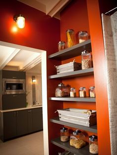 a kitchen with red walls and shelves filled with food