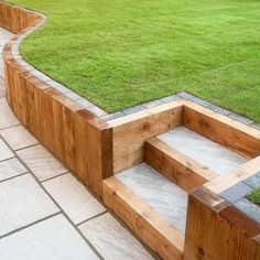 a wooden bench sitting in the middle of a lush green field next to a stone walkway