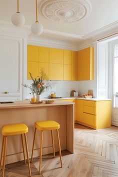 two yellow stools sit in front of an island counter with flowers on the top