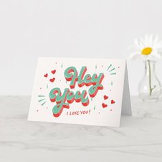 a card with the words hey you i love you on it next to a flower