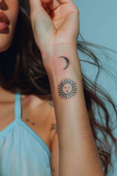 a woman's arm with a small sun and moon tattoo on the left wrist