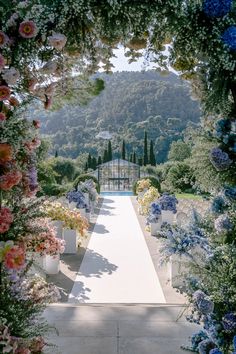 an outdoor ceremony with flowers and greenery on the walkway leading up to the entrance