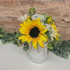 a mason jar with sunflowers and baby's breath