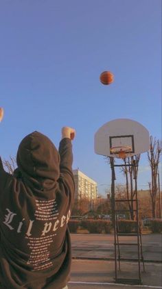 a person in a hoodie throwing a basketball into the air