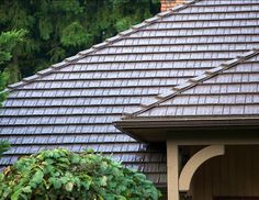 a bird is perched on the roof of a house with trees in the back ground