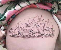 a woman's thigh with an image of dinosaurs in the sky and stars on it