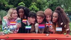 a group of people standing around a table with flags on it and one person holding a drink