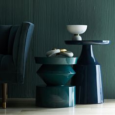 two blue vases sitting next to each other on top of a wooden floor in front of a green wall