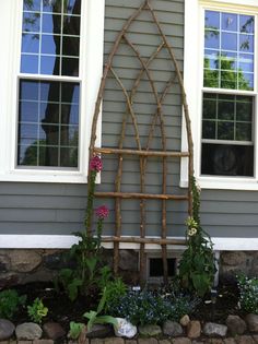 a wooden trellis sitting in front of a house next to a flower bed and window