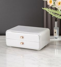 a white box sitting on top of a table next to a vase filled with flowers