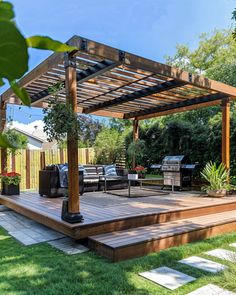 an outdoor patio with wooden decking and pergolated area, surrounded by greenery