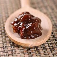 a wooden spoon filled with jelly on top of a table