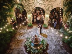 a bride and groom are standing in the middle of a courtyard surrounded by greenery